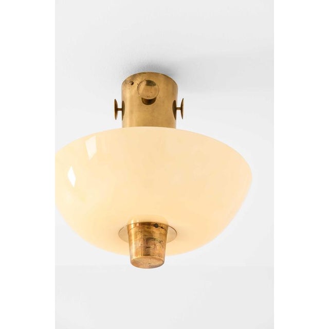 This rare ceiling lamp, designed by Paavo Tynell and produced by Taito Oy in Finland, stands as a refined example of...