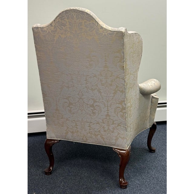 Beautifully crafted Southwood wingback chair featuring an elegant camelback silhouette, gracefully rolled arms, and richly...