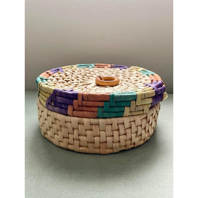 A jewel tone wide weave lidded basket with a Bakelite style handle in a circular pattern. Ships within 1-2 days using...