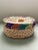 A jewel tone wide weave lidded basket with a Bakelite style handle in a circular pattern. Ships within 1-2 days using...