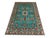 A turquoise Kazak-design wool rug with a geometric tribal pattern. Red, cream, navy, and soft green motifs stand out...