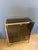 This brass and smoked glass display cabinet rests on four square feet. It has four shelves: three interior shelves and a...
