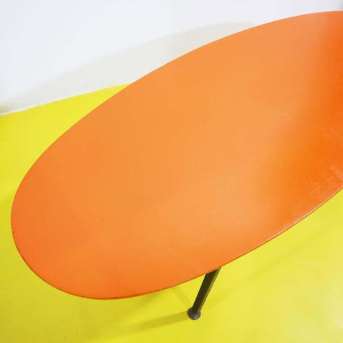Oval coffee table featuring an orange wooden top and a metal base from the 1970s.
