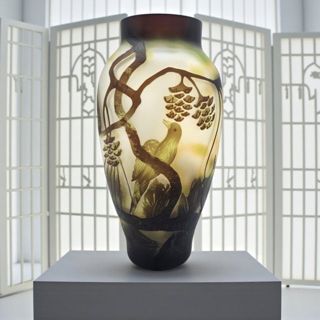 A Chinese Peking glass vase executed in a layered overlay technique, with the surface carved to reveal a bird and pine...