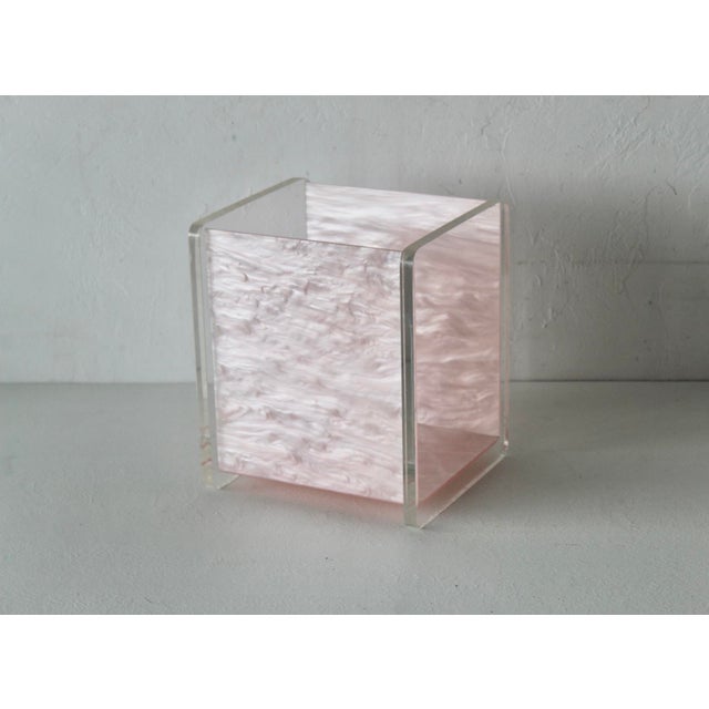 A vintage 1960s pearlized light pink acrylic and Lucite bathroom wastebasket, featuring a clear outer frame and a...