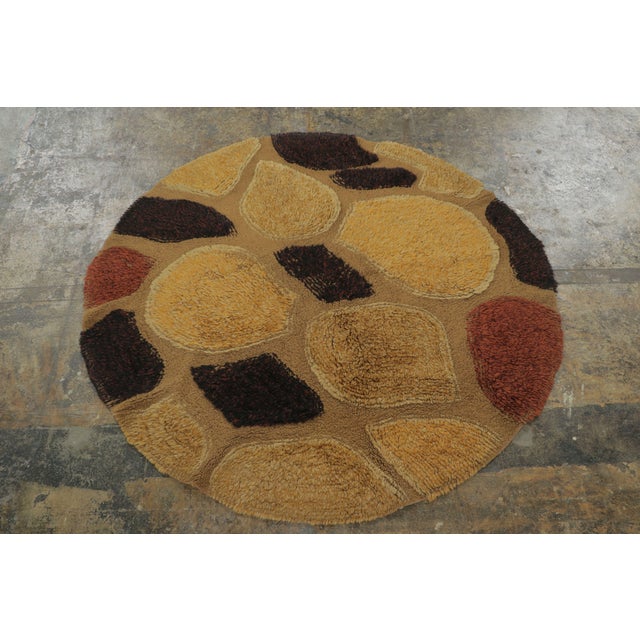 Hand knotted in wool and originating from Europe, circa 1950-1960, this 4x4 vintage circle rug enjoys an intricate, yet...