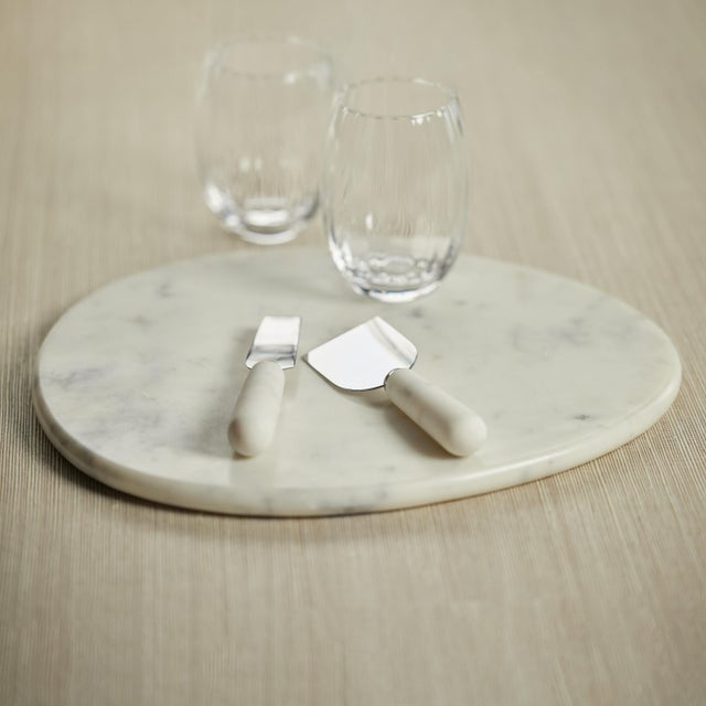 A solid slab of white marble with its smooth, substantial design features an ample, free form accentuated by natural,...