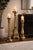 A striking trio of oversized floor candlesticks, finished in a rich, layered sunlit brass tone with subtle aged...