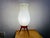 Large tulip-shaped Atomic Age table lamp on a tripod base. Made of semi-transparent plastic shade and red plastic tripod...