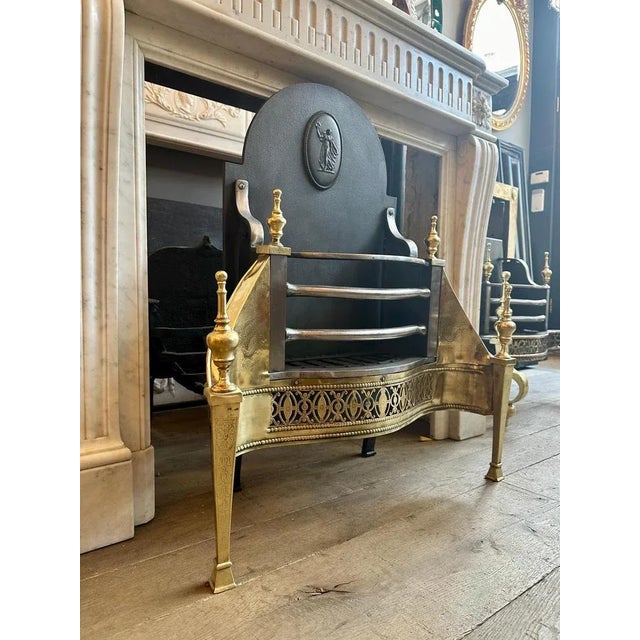 An unusual English Mid 19th century fire grate in the earlier Georgian manner. The tall shaped original fireback decorated...