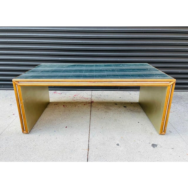 Stunning coffee table in the Hollywood regency style have a giltwood frame encasing an antique mirror top and side panels....