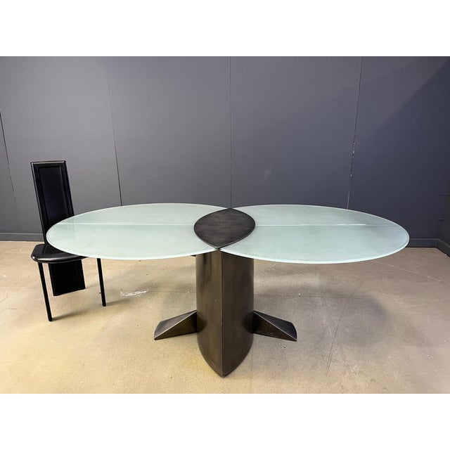 Striking postmodern design dining table consisting of a brushed aluminuml base with two matte glass table tops and a brass...