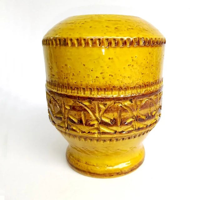 This ceramic vase features hieroglyphics motifs etched on the whole surface covered with yellow glaze.