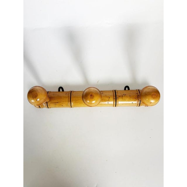 An elegant wall-mounted coat rack made of turned solid wood, featuring three generously sized spherical pegs. Its refined...