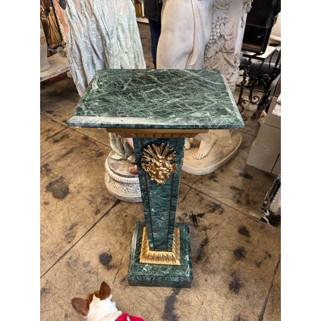 This antique green marble pedestal is a striking piece featuring rich veining and elegant gold detailing. The tapered...