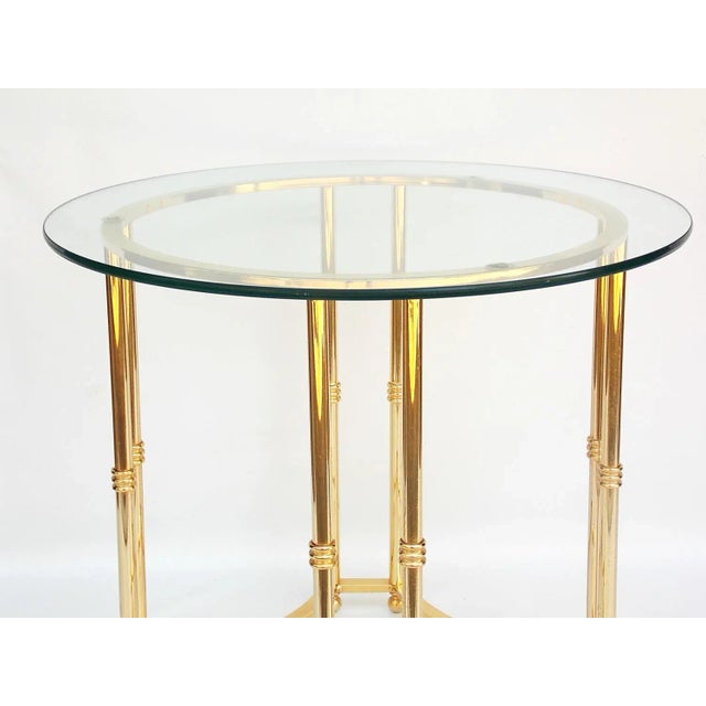 Brass side table with round glass top. Glass top, 24"Dia; base, 19.25"Dia x 20.5"H. No maker's mark.