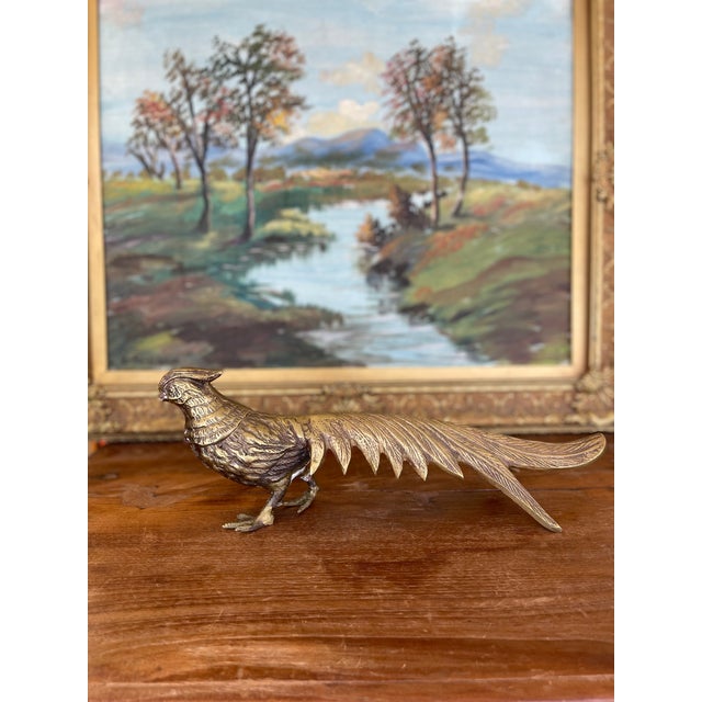 A vintage brass toned pheasant sculpture featuring finely detailed feathering and an elongated tail. This decorative piece...