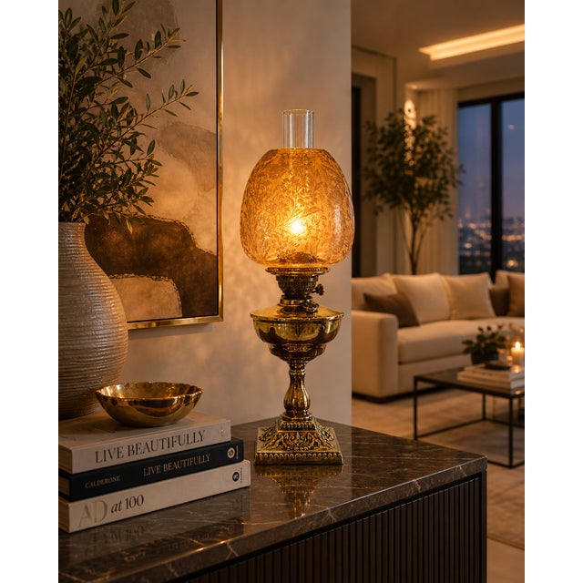 An antique Victorian brass oil lamp with an ornate base and a beautifully etched amber glass shade. The shade is finely...
