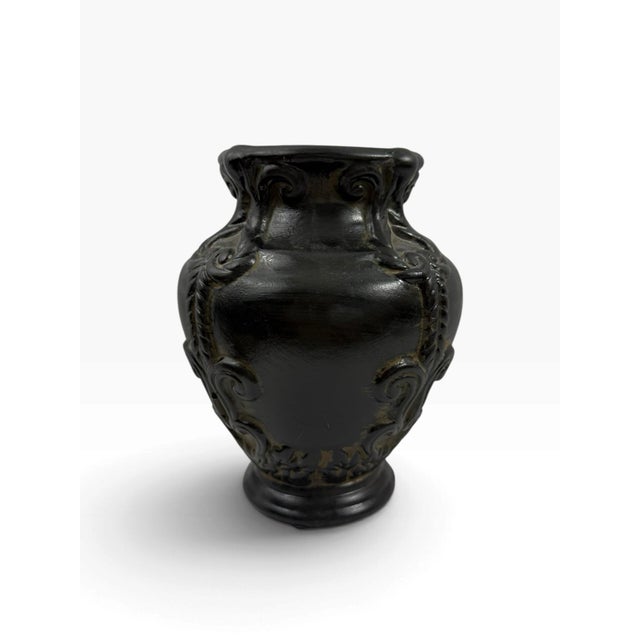 Decorative urn vase with classical scroll and leaf motifs molded in relief around the body, finished in black with a...