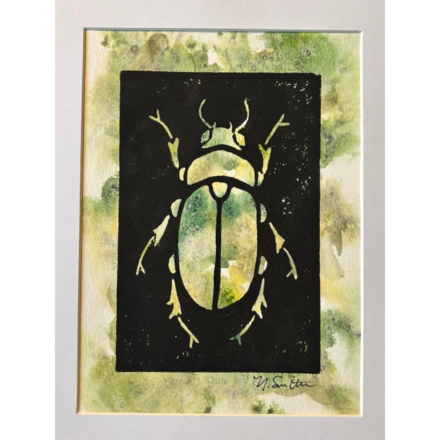 An original hand-carved block linocut featuring a detailed beetle motif, individually printed with black ink and finished...