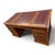 A large writing desk with two drawer pedestals and a red leather top with a gold-tooled border. Drawers with brass handles...