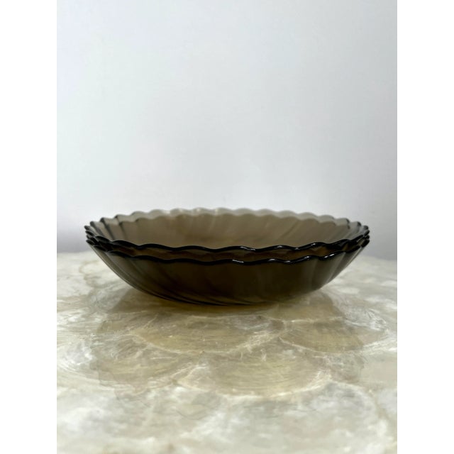 A set of two scallop-edged bowls in smoky glass. The underside of the bowls have a fine texture resulting in a matte...