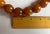 Large natural Baltic Amber worry beads strung on a fabric cord. Each round bead measures under 1" diameter. Strand...