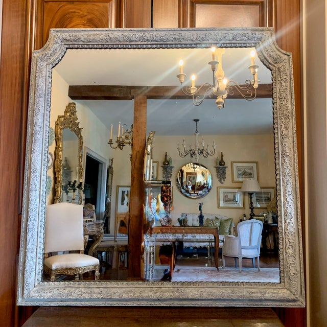 A finely carved 18th century French mirror with a weathered pale grey painted finish, the details are beautifully...