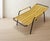 A distinctive vintage lounge chair from the 1970s, featuring a tubular metal frame with a flexible woven yellow cord seat...