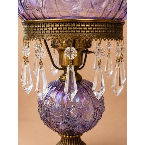 A striking vintage hurricane lamp featuring an iridescent amethyst carnival glass font with an embossed rose pattern,...