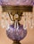 A striking vintage hurricane lamp featuring an iridescent amethyst carnival glass font with an embossed rose pattern,...
