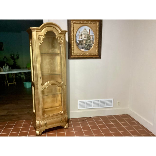 This Vintage Hollywood Regency Style Gold Lighted Curio Display Cabinet from the 1940s exudes elegance and charm. Crafted...
