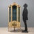 Lacquered and painted corner display cabinet in Late Baroque style. Central glass door surmounts a painted panel depicting...