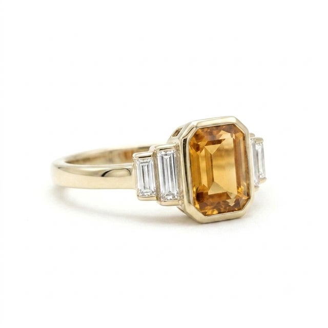 Refined and architectural, this stunning ring features a radiant 7x5mm emerald-cut citrine, secured in a sleek, protective...