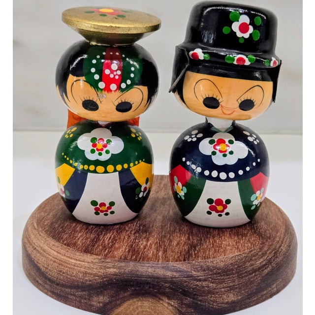 Vintage hand-painted Japanese kokeshi-inspired wooden couple dolls displayed on a carved wood base, perfect for adding a...