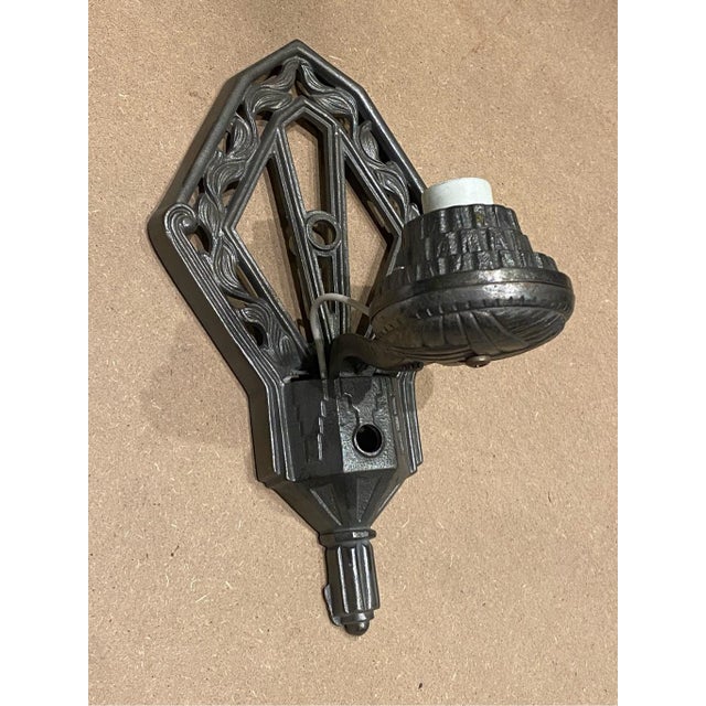 A pair of Art Deco cast iron wall sconces. The elongated diamond-shaped backplates are detailed with raised, organic...