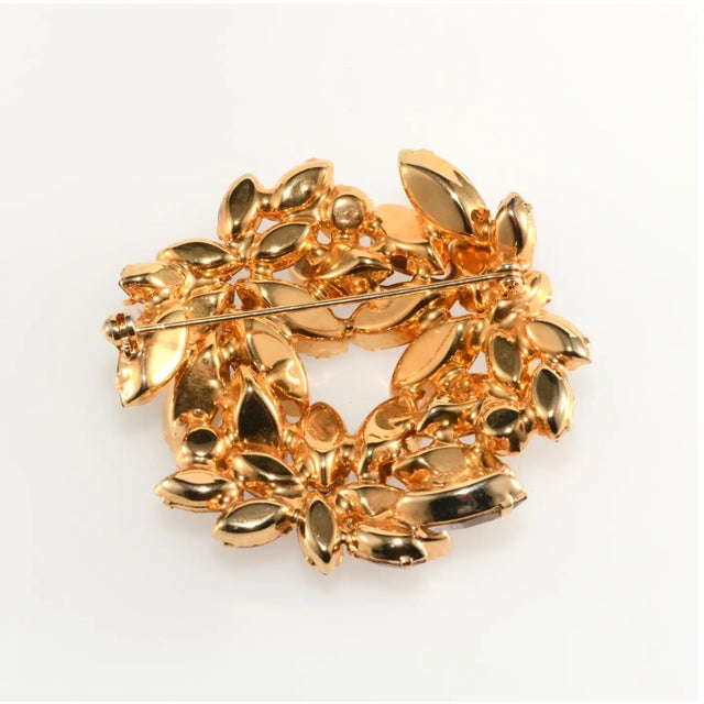 Vintage brooch embellished with a bevy of rhinestones in brown, amber, and yellow hues. Metal is gold-plated. We believe...