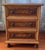 A distinctive vintage three-drawer chest featuring richly figured burl wood veneer panels framed by contrasting dark...