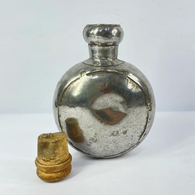 Vintage metal bottle from India with a rounded body and wooden stopper. Made from polished metal with visible wear and...