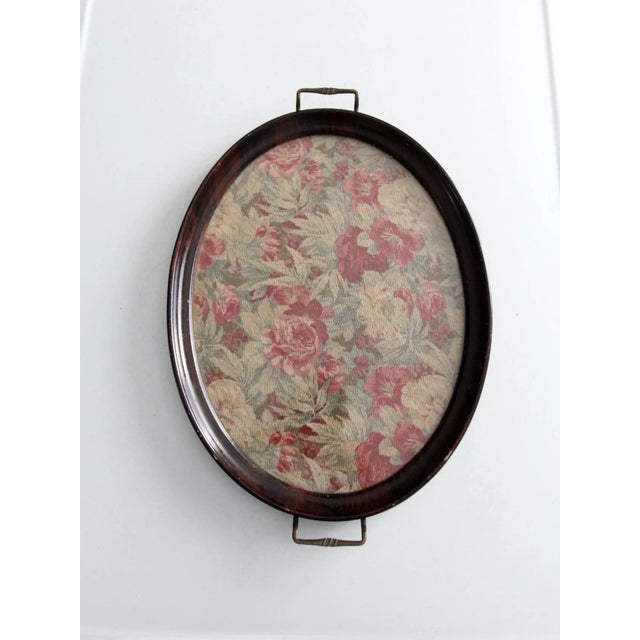 This antique Victorian serving tray features an elegant oval wooden frame with brass handles and a floral textile base...