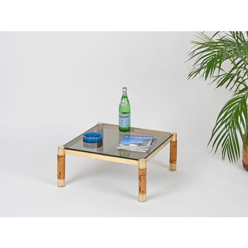 Marvelous coffee table crafted in a refined combination of solid brass and bamboo, completed with a thick smoked glass...