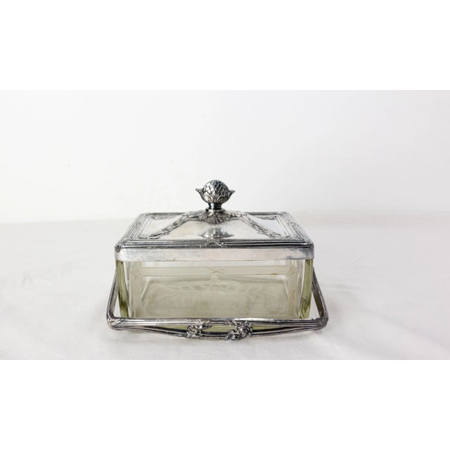 Small engraved glass box framed with nickel-plated spelter with it matching lid and a handle. The decoration of the box...