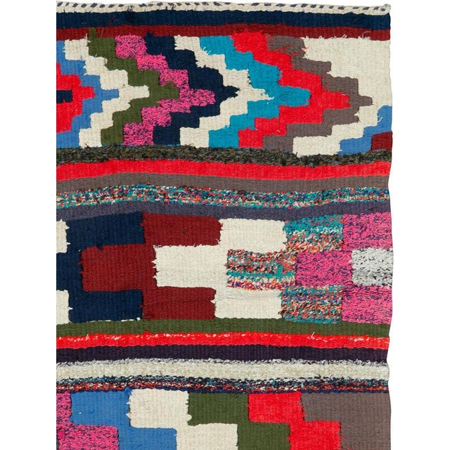 This mid-20th century Persian flatweave kilim rug is a vivid expression of tribal design, characterized by its bold...