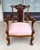 This Victorian walnut armchair features an ornately carved crest rail with scrolling floral details and a decorative...