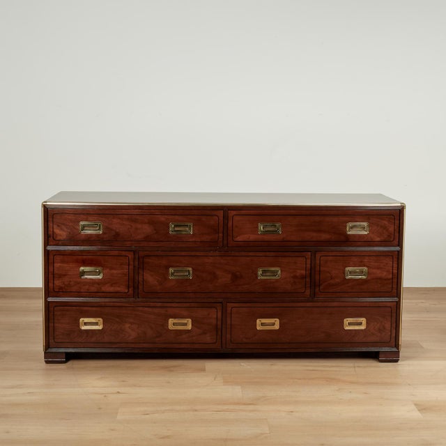 Chic mid century dresser crafted in mahogany with seven drawers uniquely off set, campaign style brass hardware and block...