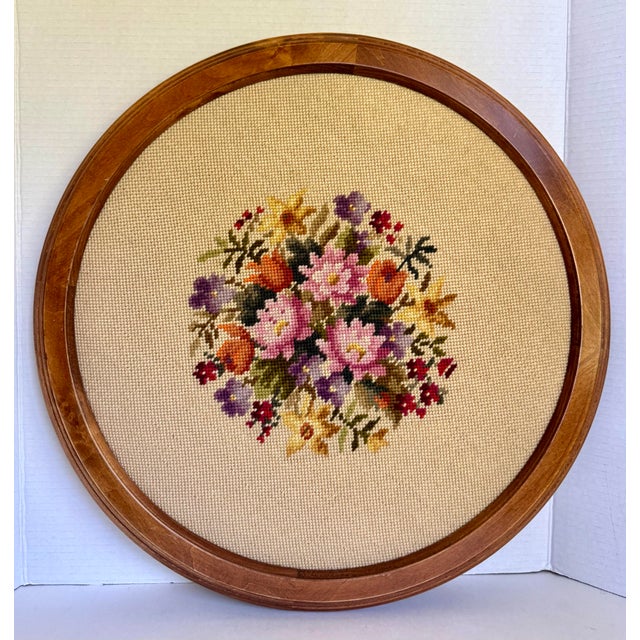 Here is a vintage hand-stitched floral needlepoint wall hanging presented in a handsome round wood frame. Featuring a...