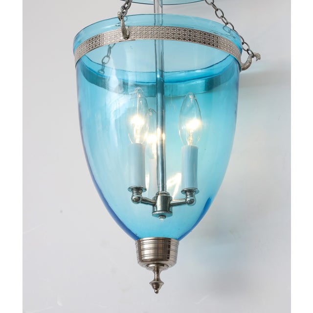 A single hanging glass pendant in soft aqua blue with nickel hardware. Features three interior arms for bulbs and hangs...