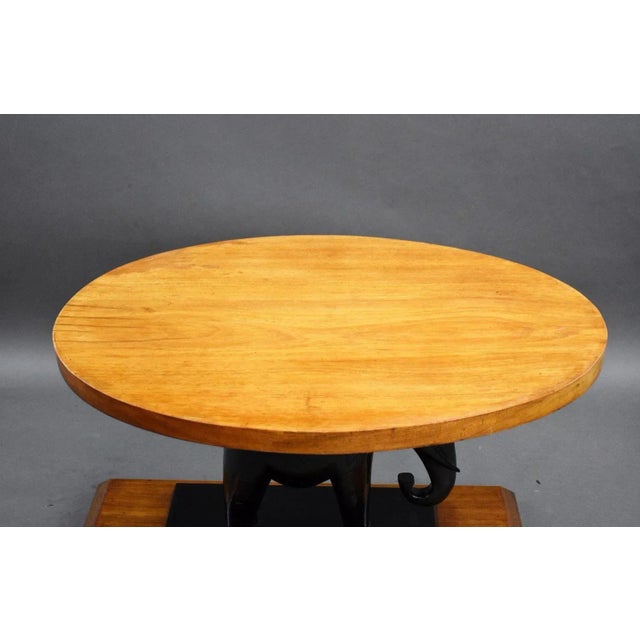 Deco Ebony Elephant walnut coffee table in good condition with oval top sitting on an ebony elephant on walnut base. The...