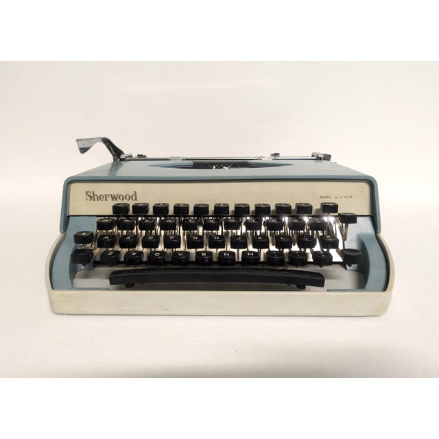 A mid-century Italian typewriter from the 1960s. The vintage portable typewriter is blue and cream with a gray soft gray...