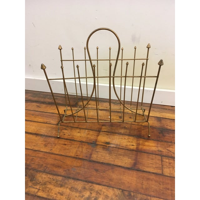 Mid century magazine rack. Gold on metal finish. All original prongs and round feet. Nice simple graphic quality.